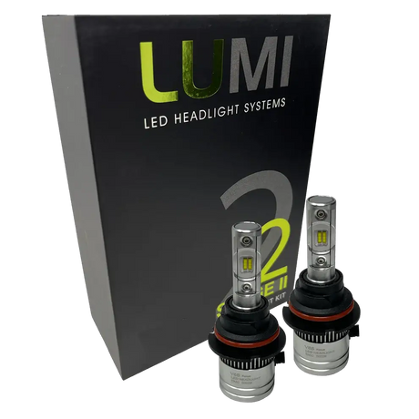 Two LUMI Stage 2 9004 LED Headlight Bulbs by Lumi are displayed in front of a black box labeled “LUMI LED Headlight Systems 2.” The bulbs have a metallic finish with prominent yellow CSP chips, delivering bright 6000K light for enhanced visibility.