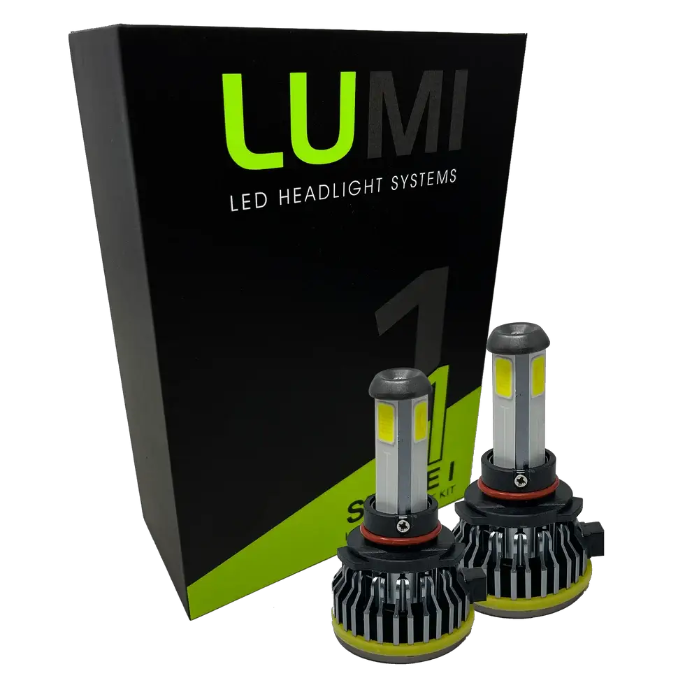 Two LUMI Stage 1 9005 LED Headlight Bulbs are displayed in front of a black and green Lumi LED Headlight Systems box. Featuring silver tops, black bases, and yellow accents, these bulbs are engineered with integrated LED CANBUS technology to deliver a bright 6000K white light for superior visibility.