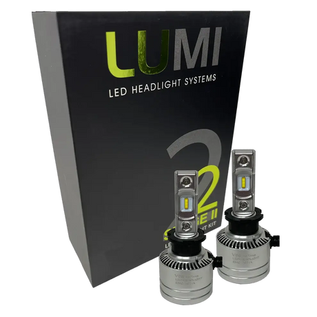 Two premium LUMI Stage 2 H3 LED Headlight Bulbs with advanced CSP chips are positioned in front of a sleek black Lumi LED Headlight Systems box labeled Stage 2, delivering brilliant 6000K color temperature illumination.