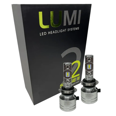 Two LUMI Stage 2 H7 LED Headlight Bulbs from Lumi, featuring advanced CSP chips, are displayed in front of a black box labeled “LUMI LED Headlight Systems S2 Stage II Headlight Kit” on a white background, providing bright 6000K illumination for superior visibility.
